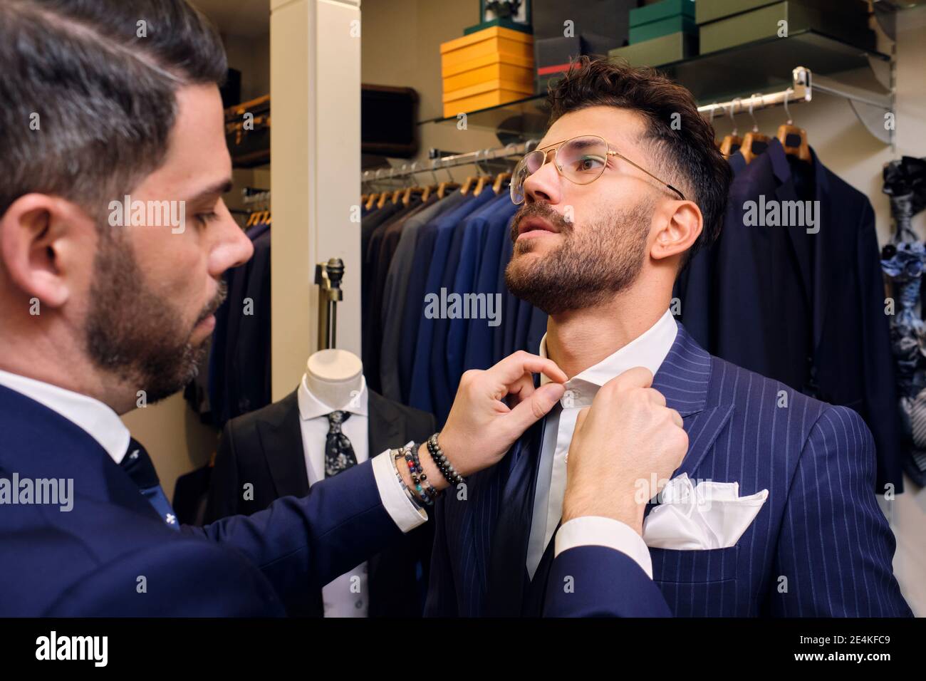 Tailor in his menswear store fastening customers collar Stock Photo