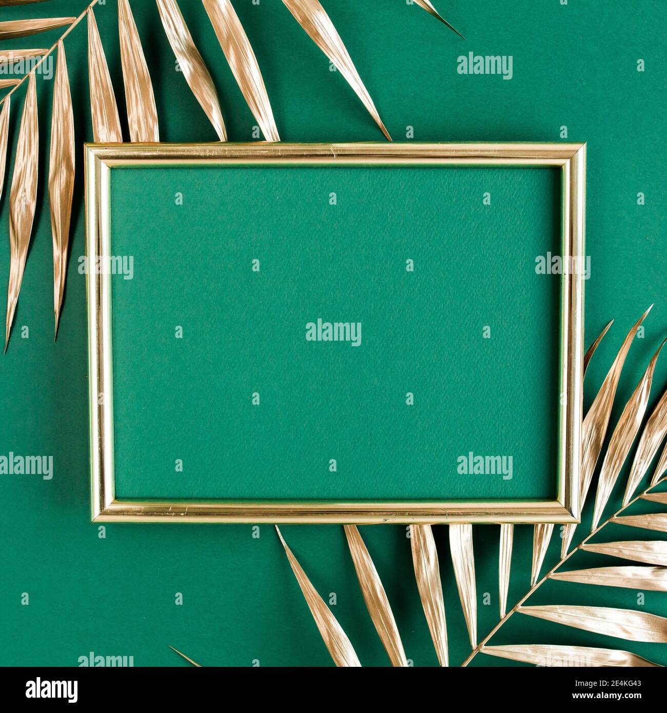 Gold tropical palm leaves and photo frame on green background. Flat lay ...