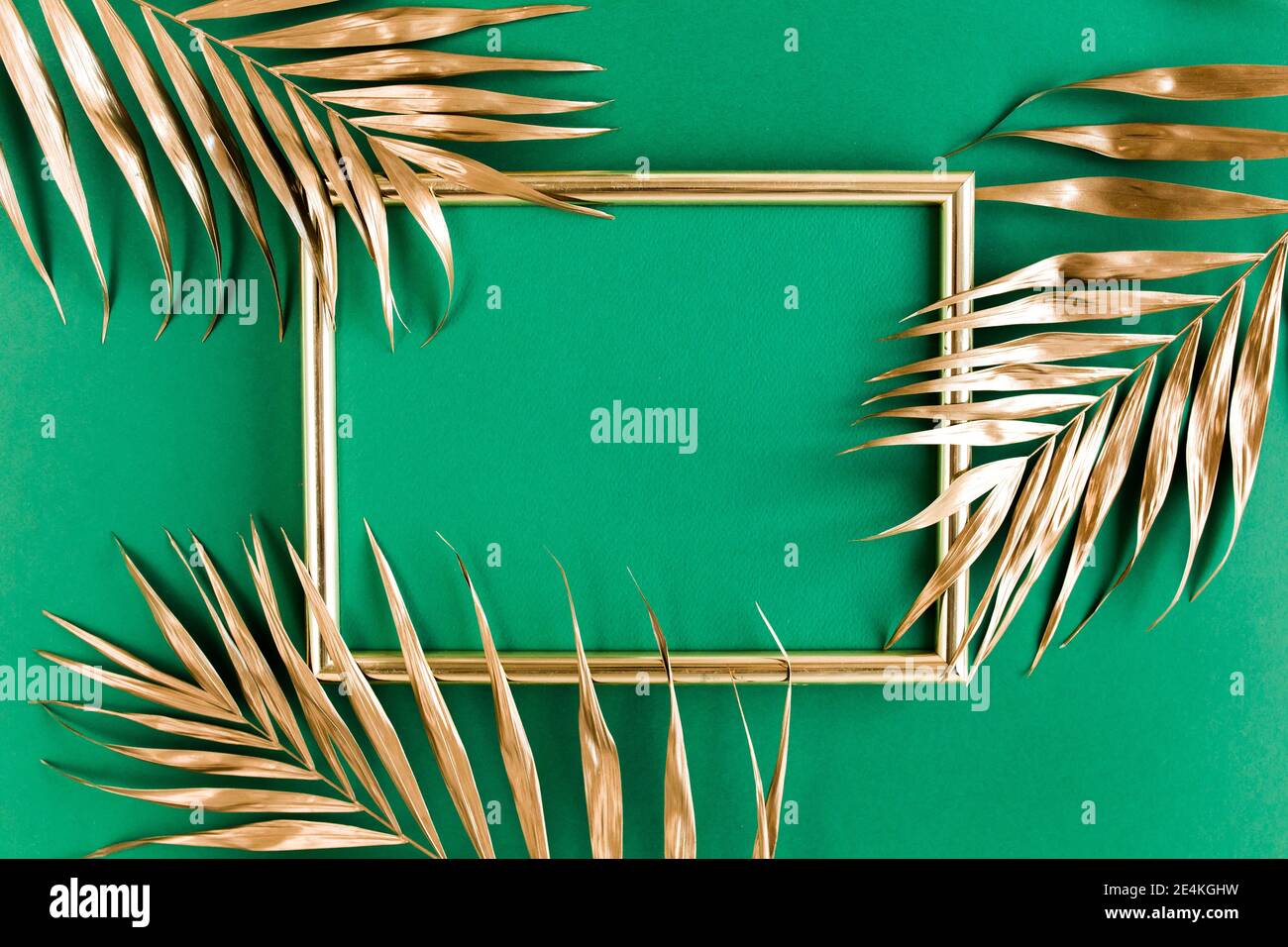 Gold tropical palm leaves and photo frame on green background. Flat lay ...