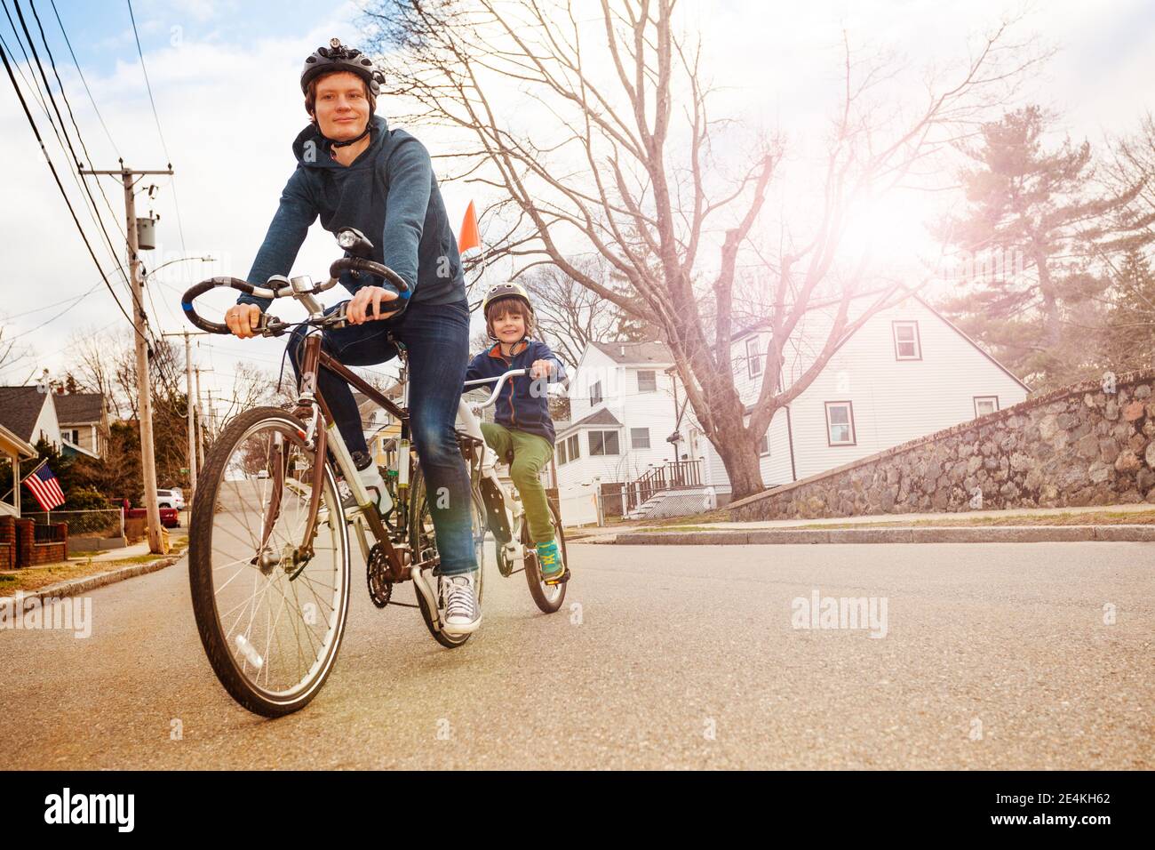 Portrait of a little boy ride on a tow tandem bike attached to father on urban street view from front Stock Photo
