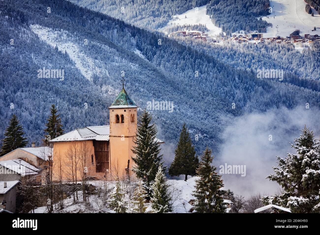 View of church in Champagny-en-Vanoise village with mist and clouds around Stock Photo