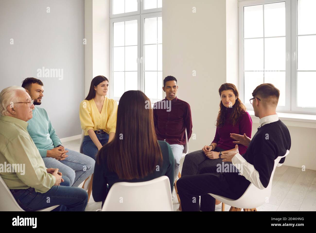 Group of people sit in a circle and each talks about their problems during a therapy session. Stock Photo