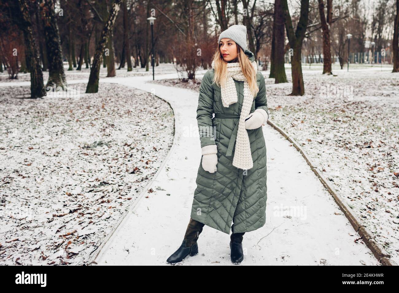 Full body portrait of young woman walking in snowy winter park