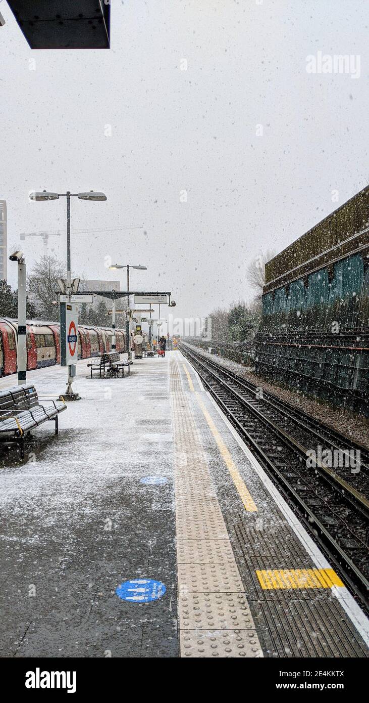 TfL worker hurriedly applies grit salt to train platform at Colindale Tube Station whilst it snows on 24th January 2021. Transport for London is unprepared for bad weather on the London underground network despite Met Office weather warnings being in place for heavy snowfall. Colindale, London. UK Weather. Stock Photo