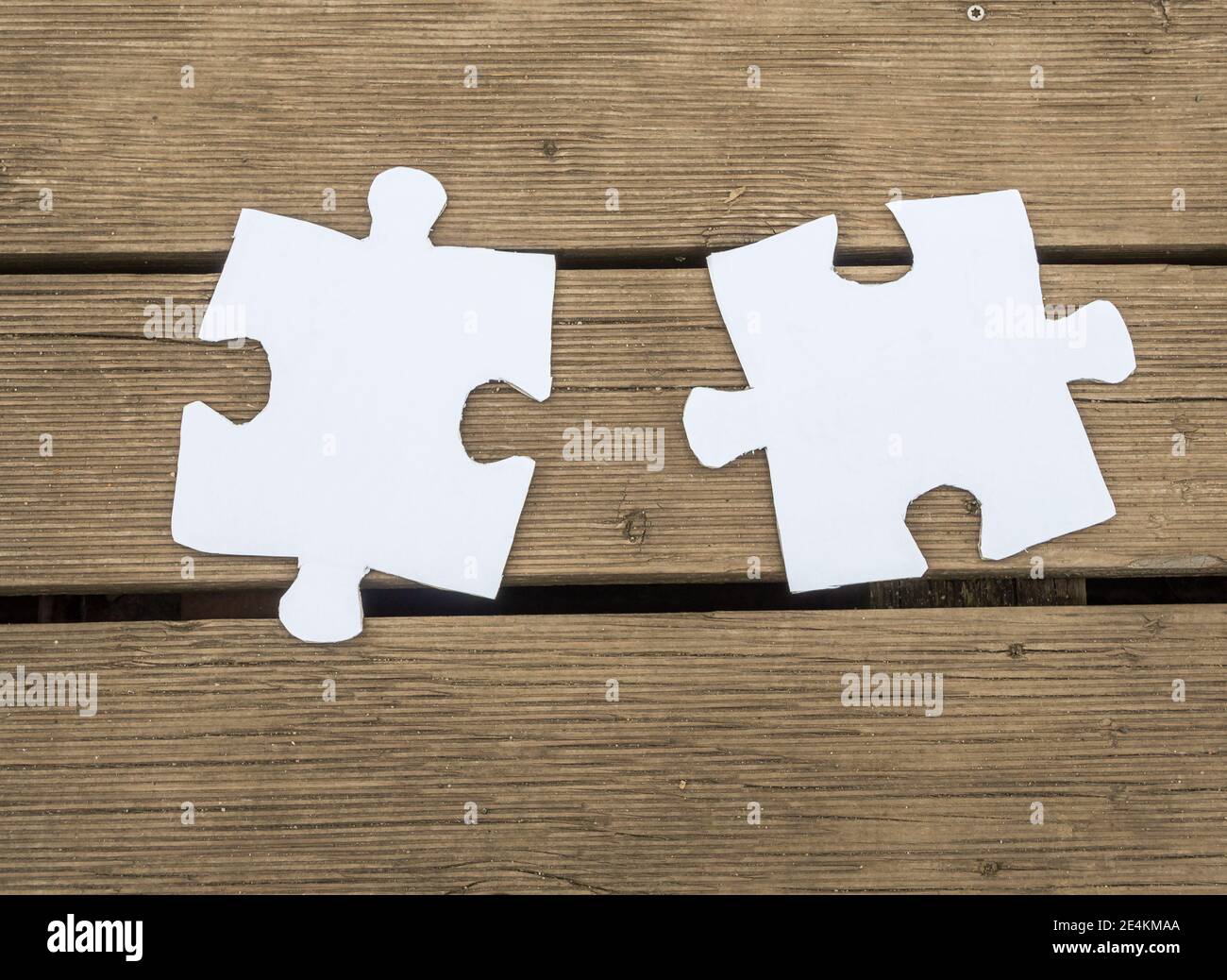 White puzzle piece on a walnut wooden table Stock Photo