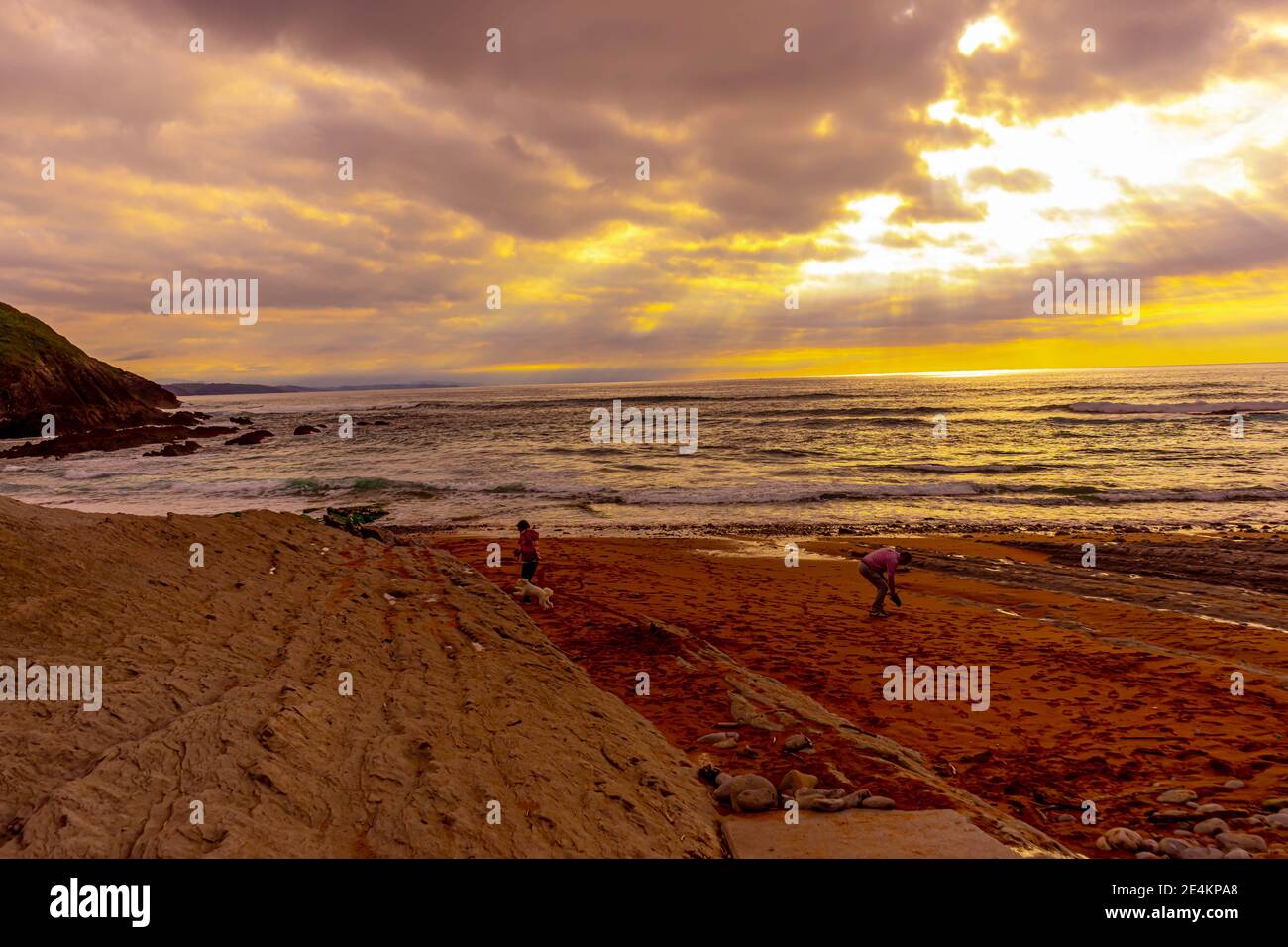 SUANCES, SPAIN - Jan 19, 2021: people on the beach watching the sunrise and water Stock Photo