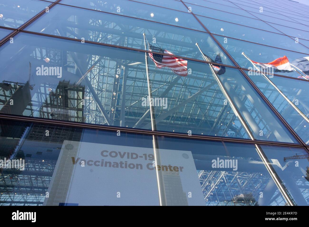New York, USA. 23rd Jan, 2021. Flags are reflected in the window of a COVID-19 vaccination center at the Jacob K. Javits Convention Center in New York, the United States, Jan. 23, 2021. The total number of confirmed COVID-19 cases in the United States topped 24.99 million, according to the data released by Johns Hopkins University on Saturday. Credit: Michael Nagle/Xinhua/Alamy Live News Stock Photo
