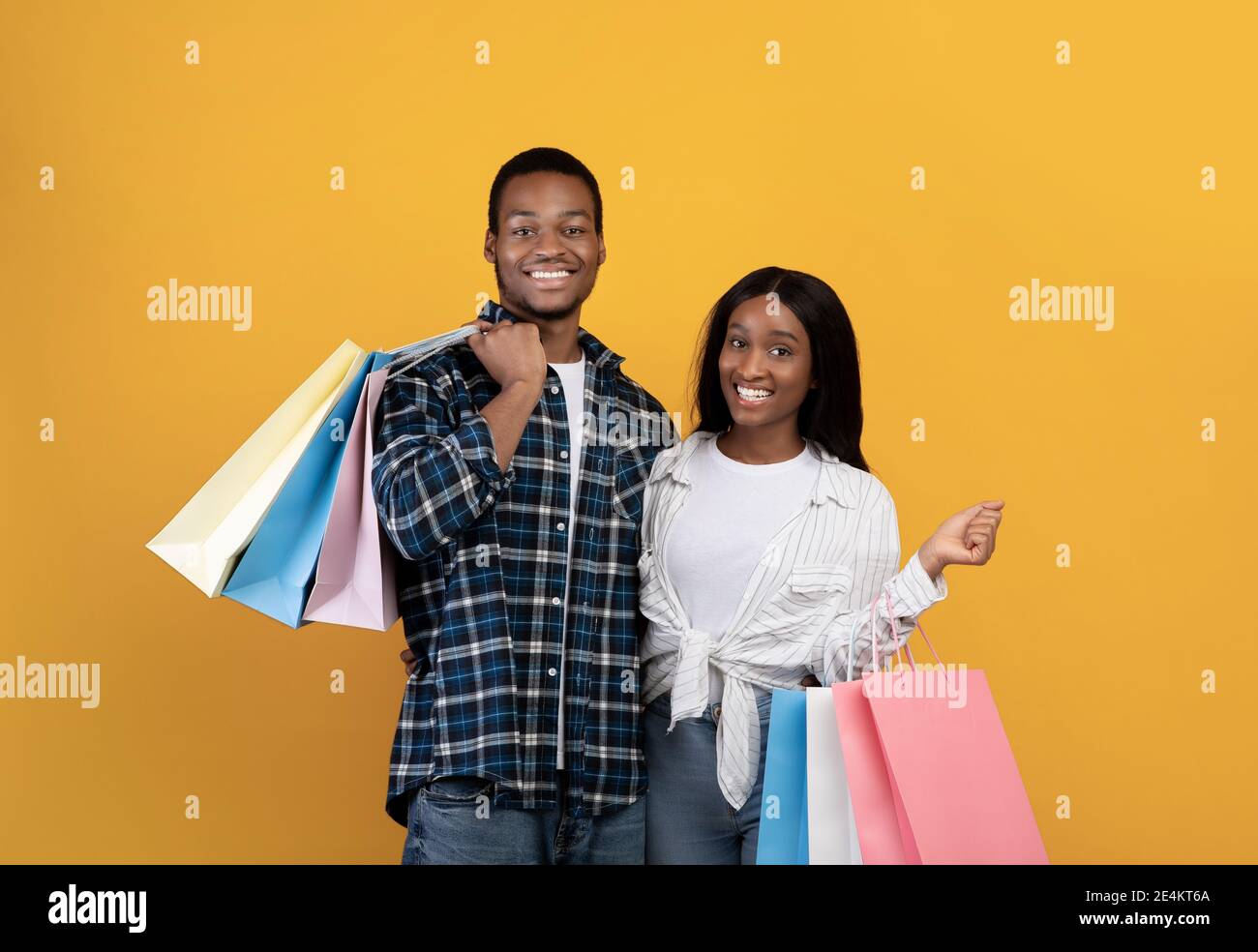 Smiling millennial african american husband and wife hold many colored ...