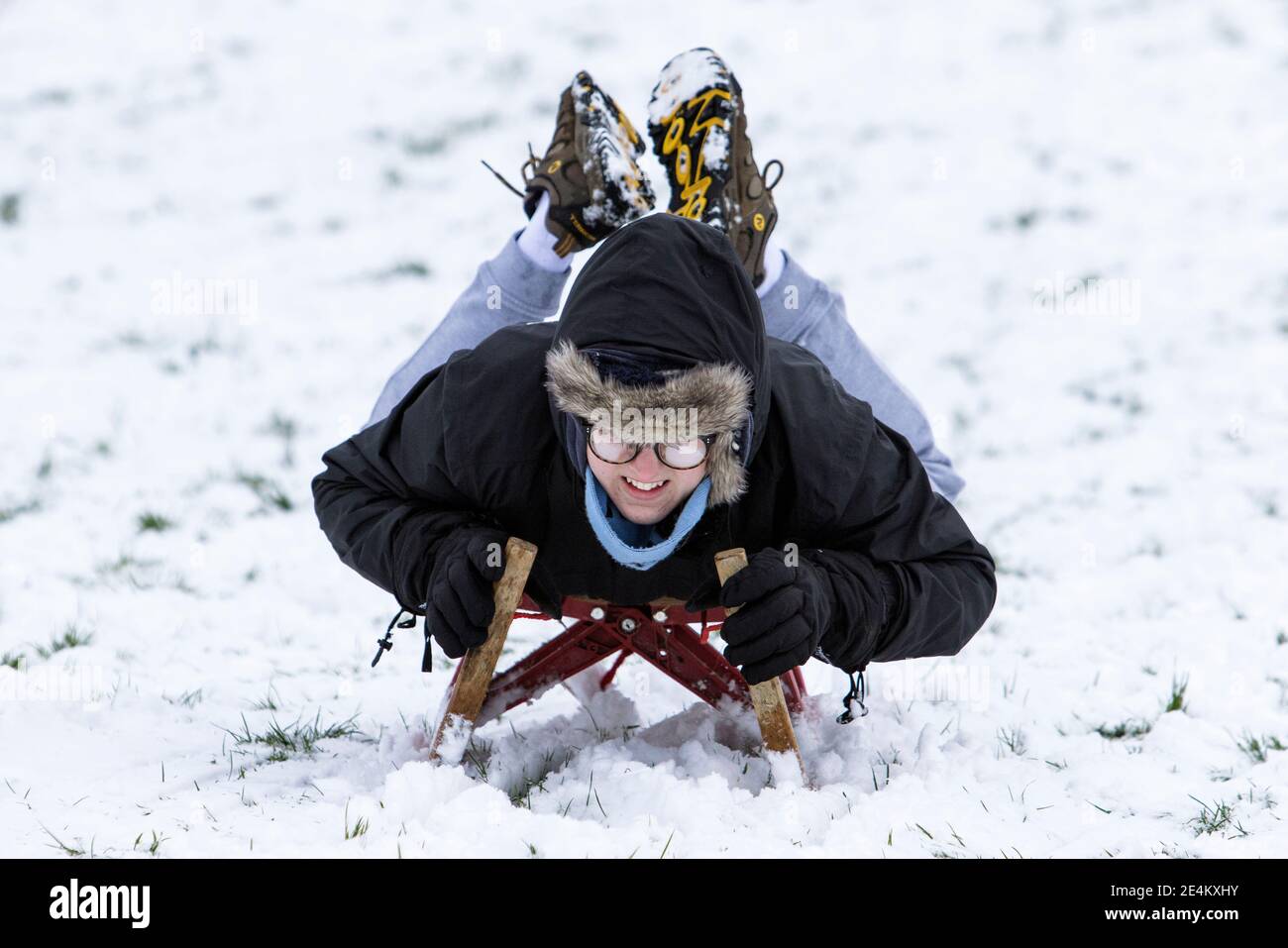 Chippenham, Wiltshire, UK. 24th January, 2021. As Chippenham residents wake up to their first snow of the year, a boy enjoying the snow before it thaws is pictured in a local park in Chippenham as he speeds down a hill on a sledge. Credit: Lynchpics/Alamy Live News Stock Photo
