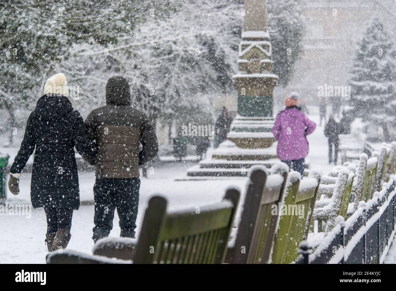 Leamington Spa, Warwickshire, UK, 24th January 2021: A couple link arms through Jephson Gardens during a snowy Sunday in January. Credit: Ryan Underwood / Alamy Live News Stock Photo