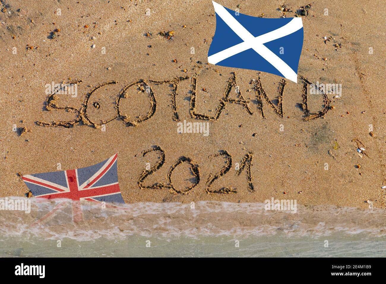 Scotland 2021 in Sand geschrieben, Schottische Flagge oben, Britische Flagge wird vom Wasser überflutet Stock Photo