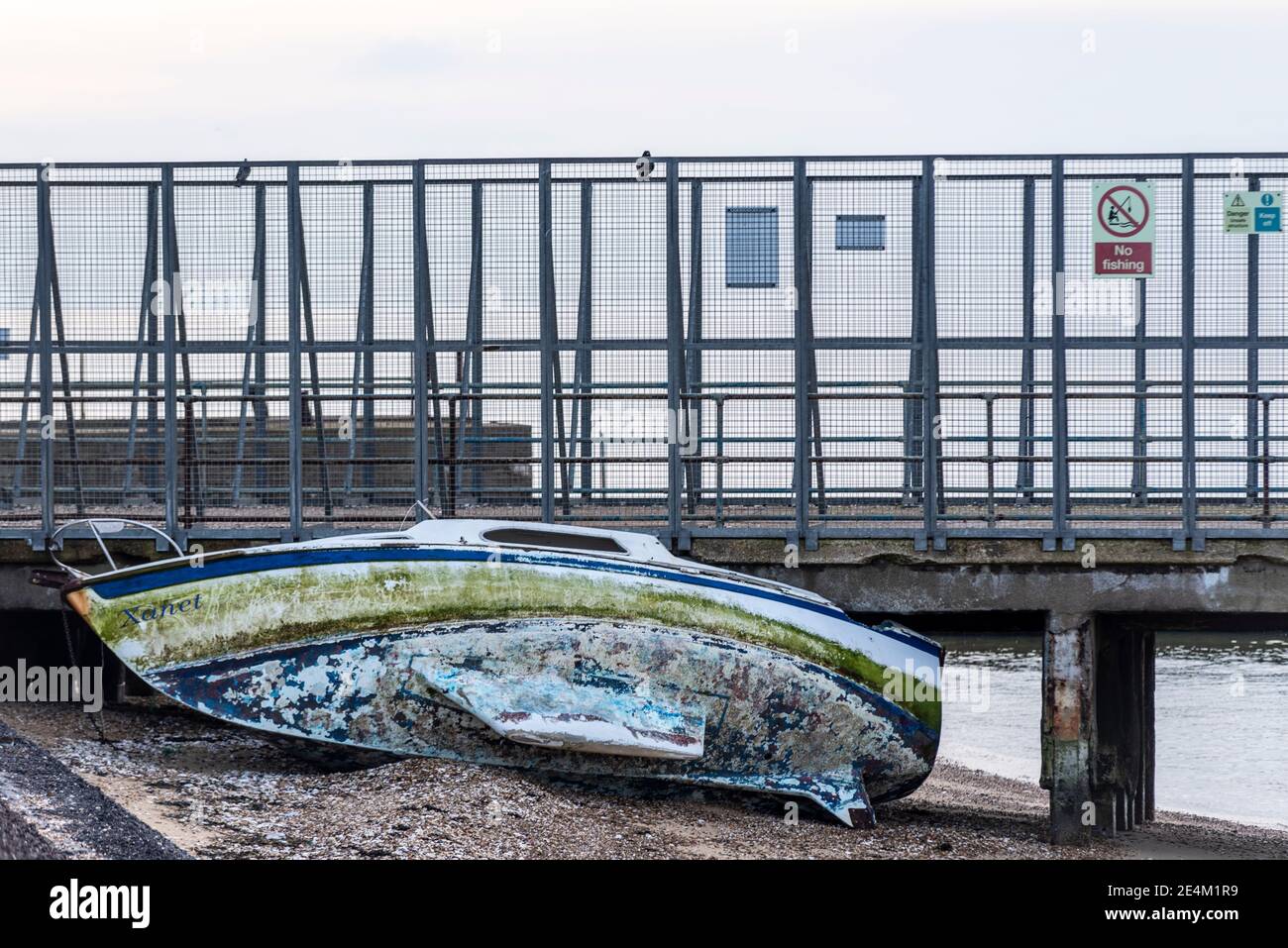 Boat named Xanet washed up onto the beach by stormy seas. Washed against Barge Pier, Shoeburyness, Essex, UK, on MoD land off limits due to ordnance Stock Photo