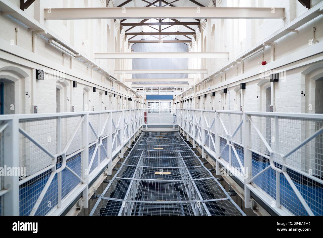 Looking into prison cell block landing victorian British English jail house bed in room lock up high security room derelict old new category A B C Stock Photo