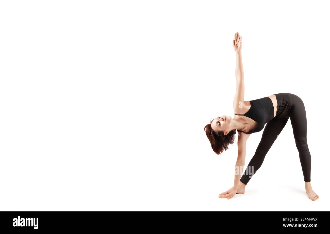 young beautiful woman in black leggings and top doing sports and yoga indoors, on a white background, isolate Stock Photo