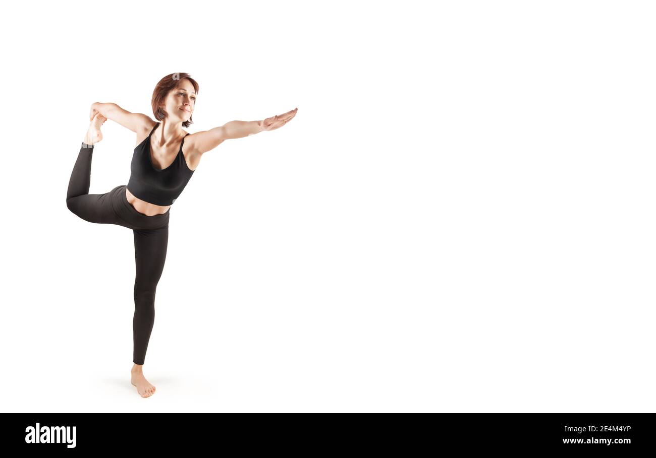 young beautiful woman in black leggings and top doing sports and yoga indoors, on a white background, isolate Stock Photo