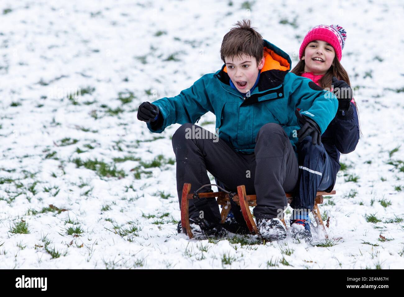 Chippenham, Wiltshire, UK. 24th January, 2021. As Chippenham residents wake up to their first snow of the year, two children are pictured in a local park in Chippenham as they slide down a hill on a sledge. Credit: Lynchpics/Alamy Live News Stock Photo