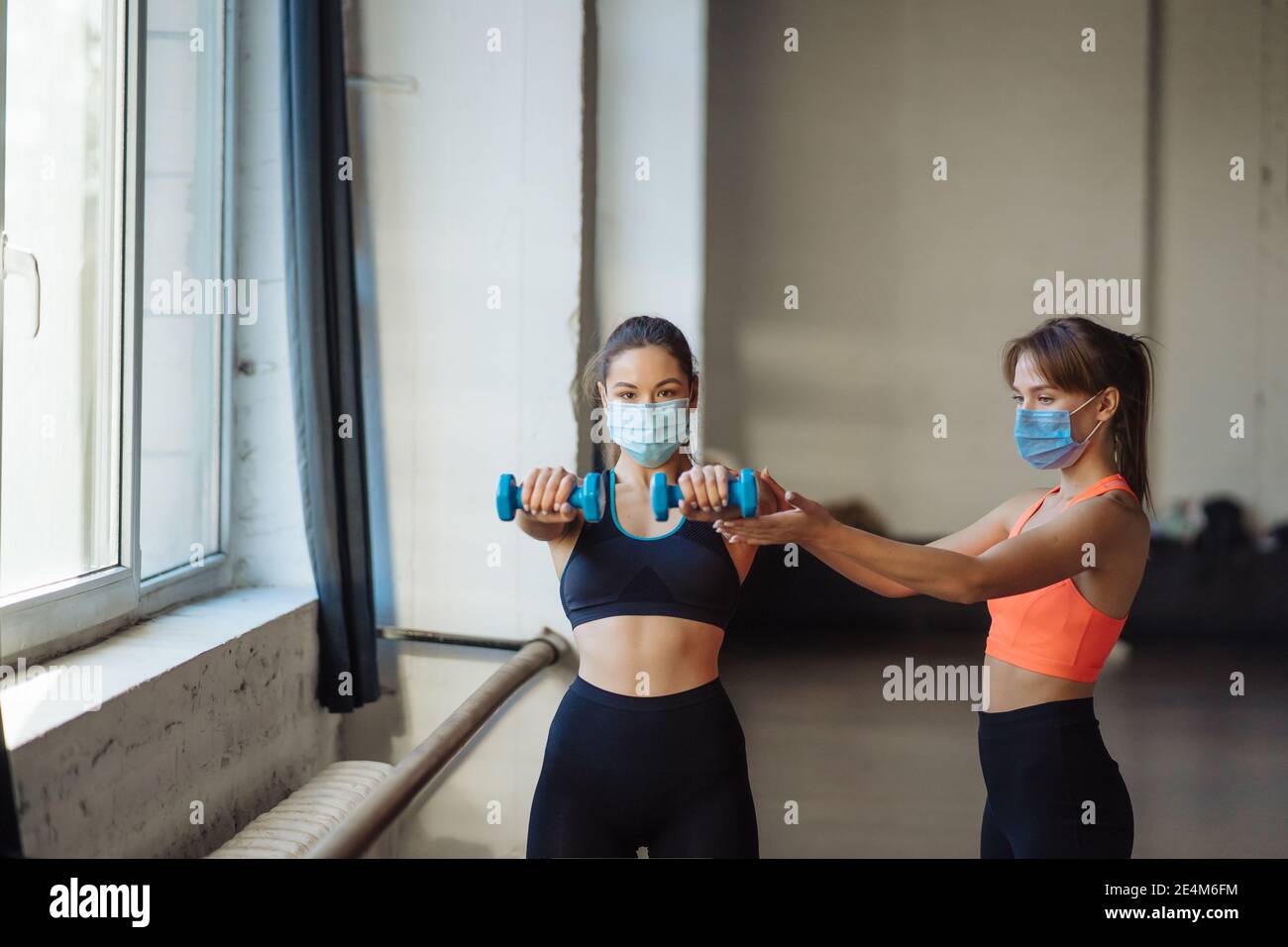 Young woman personal trainer helping with workout at gym Stock Photo ...