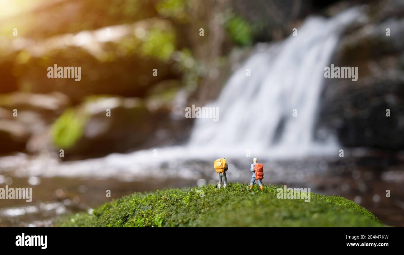 Miniature figure people backpack standing in forest with nature background Stock Photo