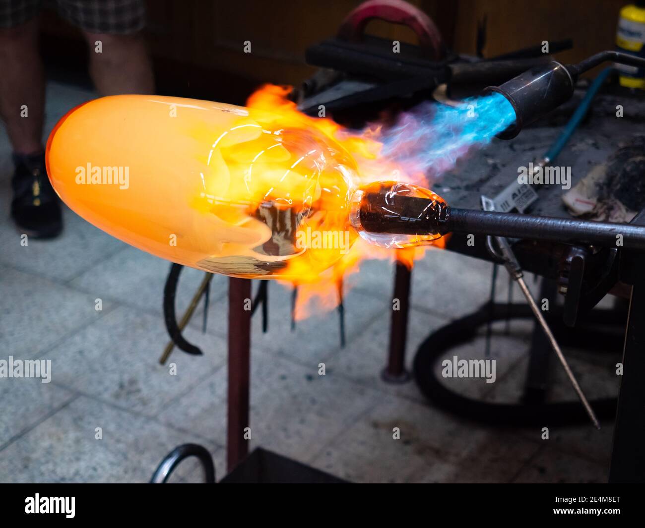 Artist glass blowing process. The glassblower master with coworkers