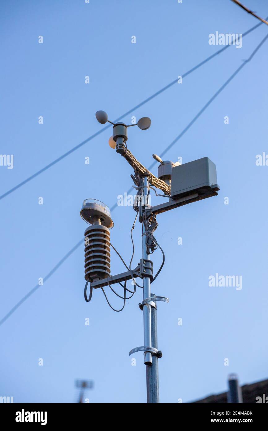 A home weather station mounted on a pole in a suburban back yard in the