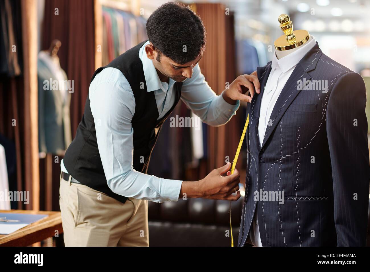 Creative young tailor measuring bespoke jacket on mannequin he is working on Stock Photo
