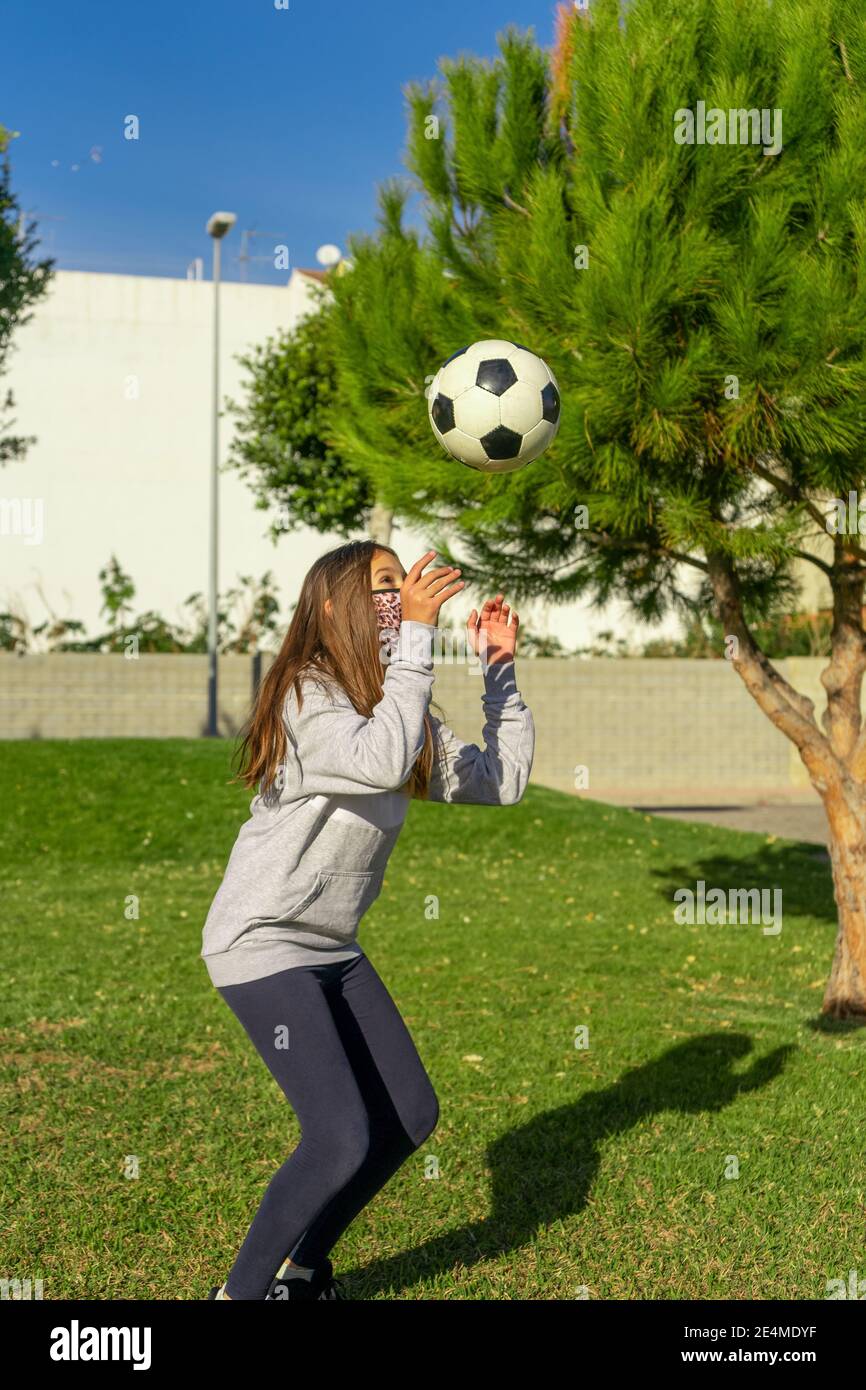 Beautiful little girl playing soccer in a nice park with natural grass ...