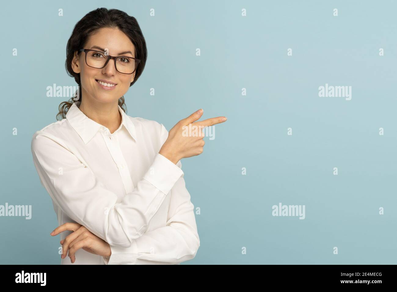Smiling business woman wear white blouse and glasses pointing with finger, showing at copy space Stock Photo