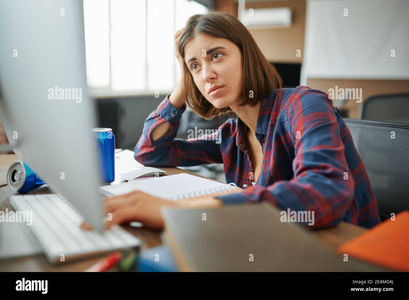 Tired IT specialist works on computer in office Stock Photo