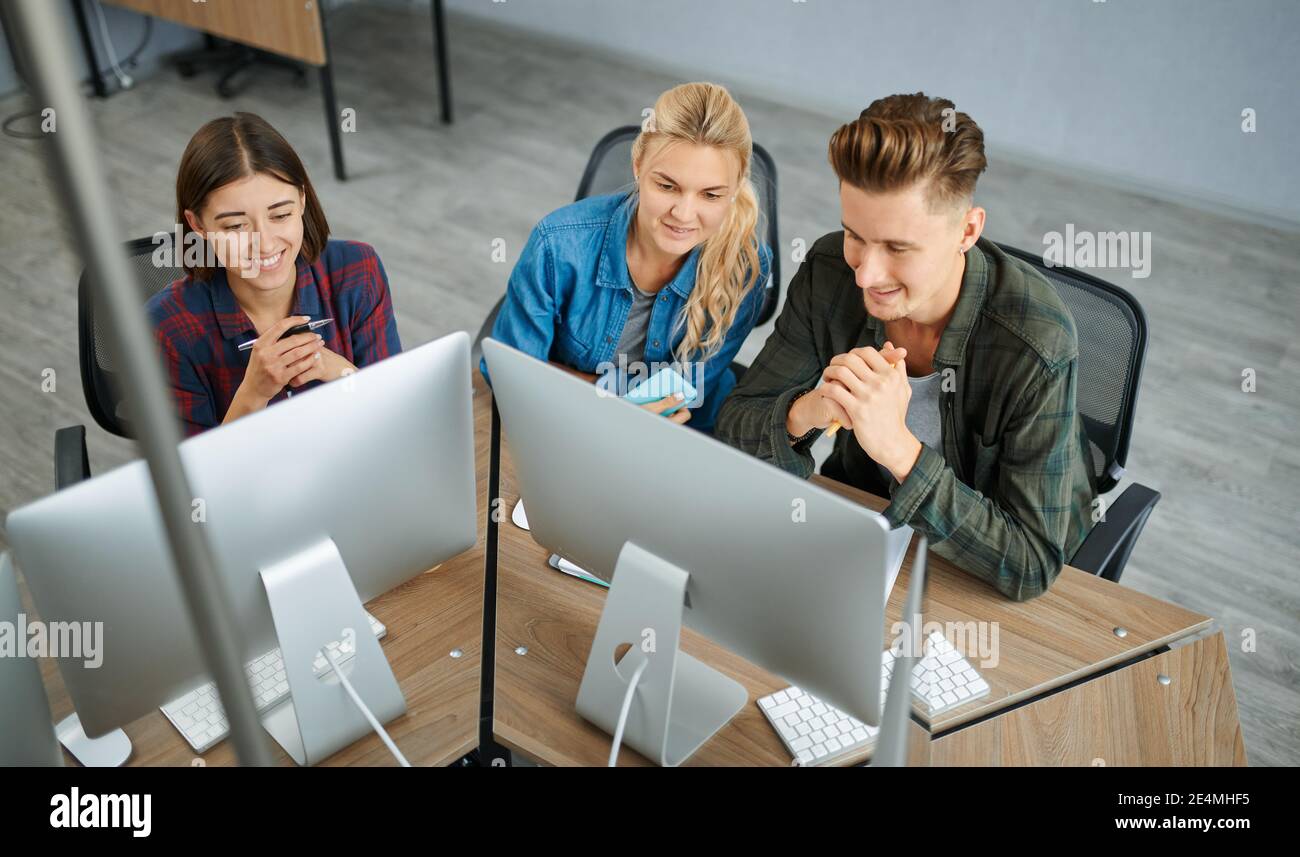 Smiling IT specialists works on computers, office Stock Photo