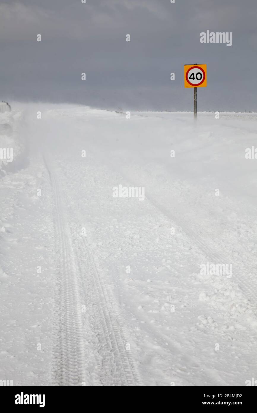 Upland country road with 40 miles per hour speed restriction sign impassable due to a heavy snowfall and drifting. Stock Photo