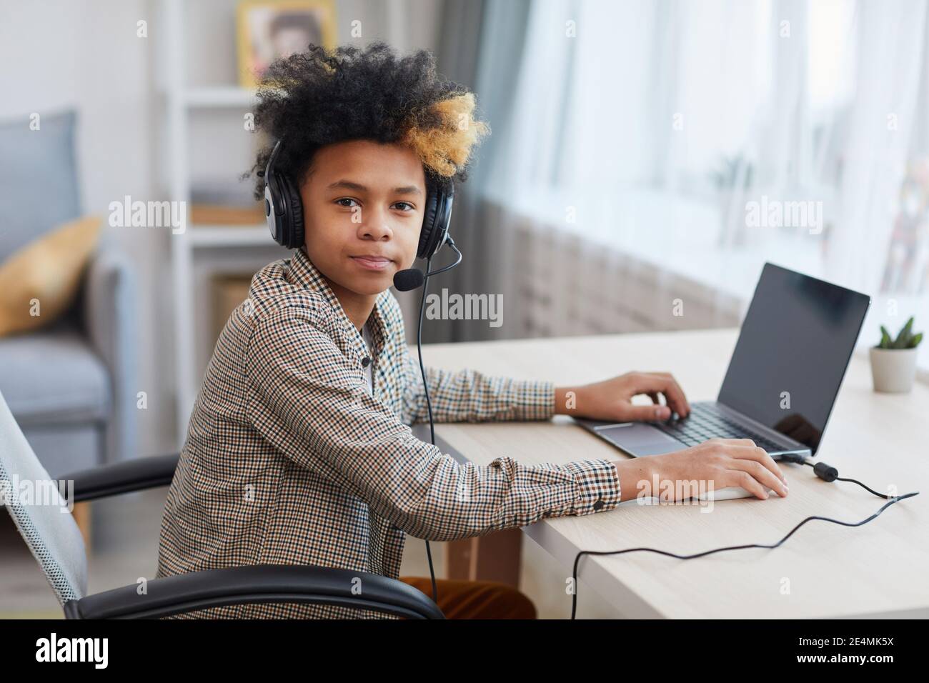 Portrait of teenage African-American boy wearing headset and looking at ...