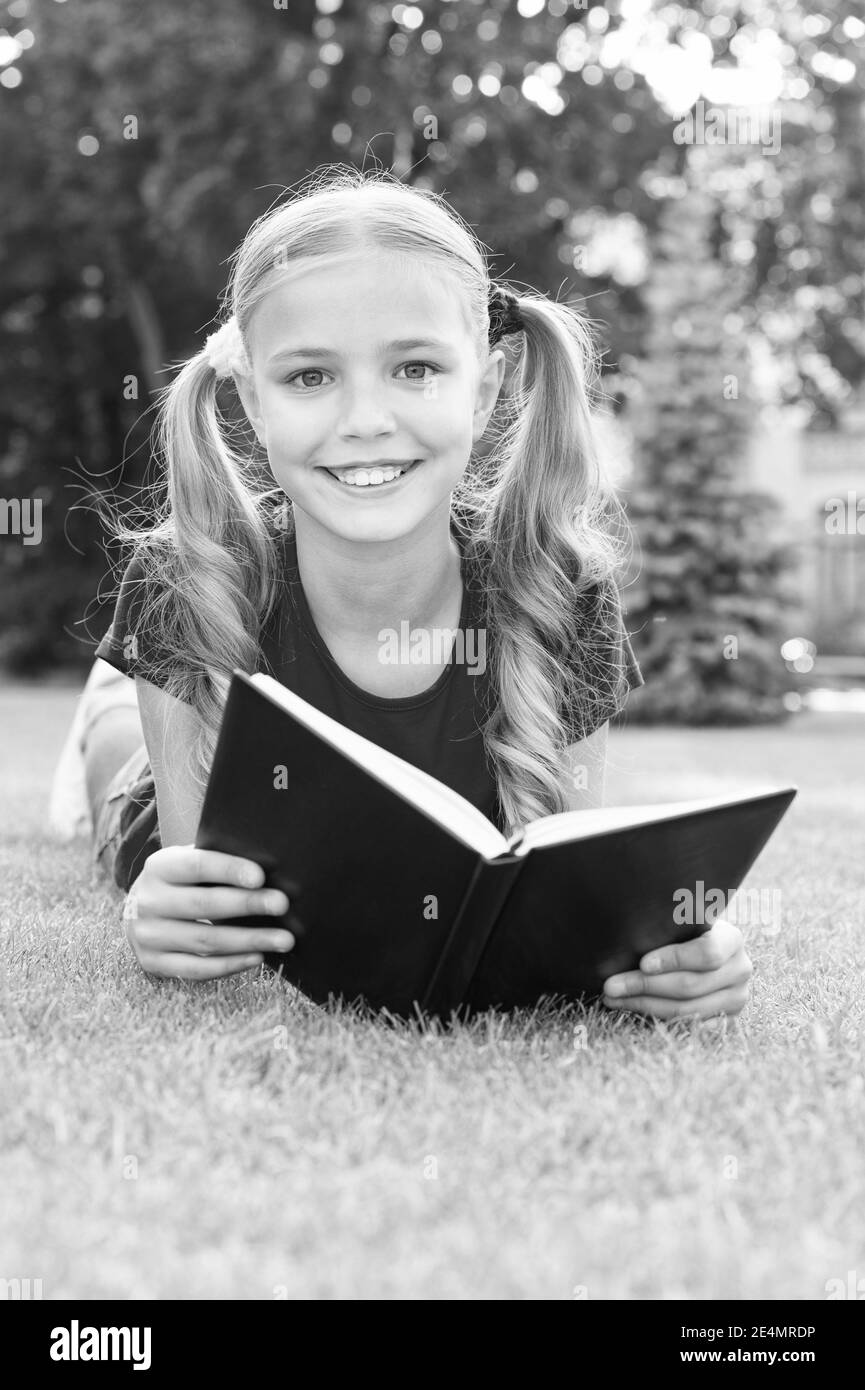 Small girl cute hairstyle reading book relaxing nature background