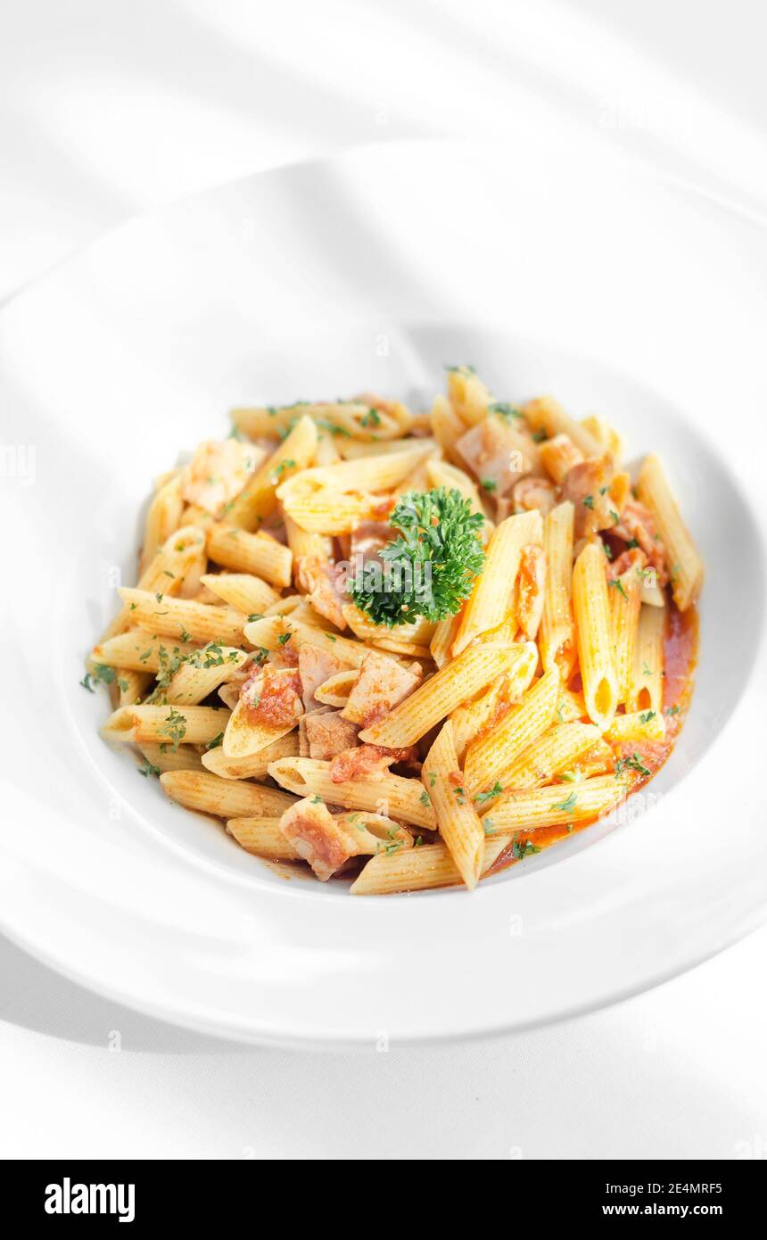 penne amatriciana organic tomato and ham sauce pasta dish on white table Stock Photo