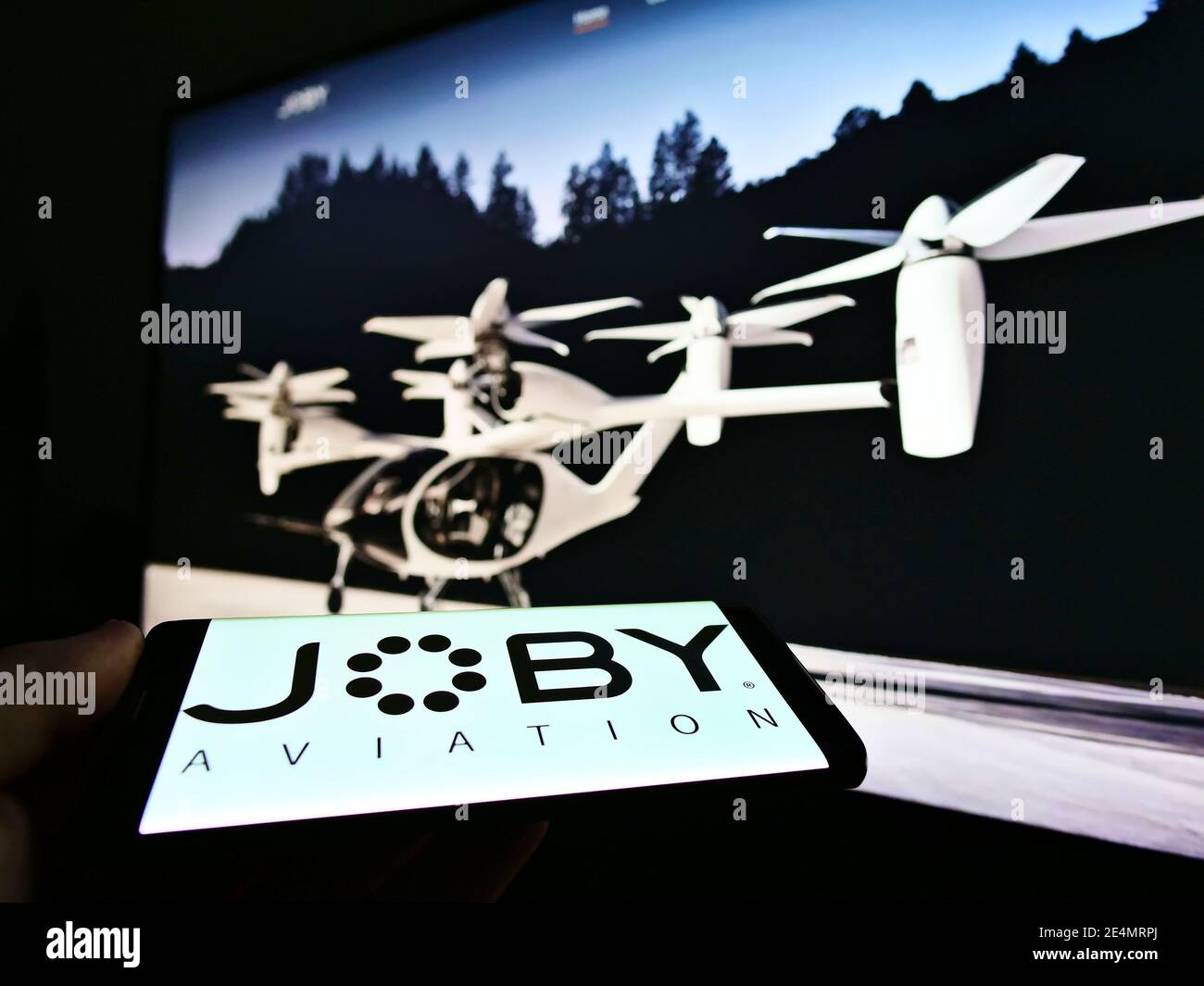 Person holding smartphone with logo of startup and aerospace company Joby Aviation (air taxi) on screen. Focus on top center of phone display. Stock Photo