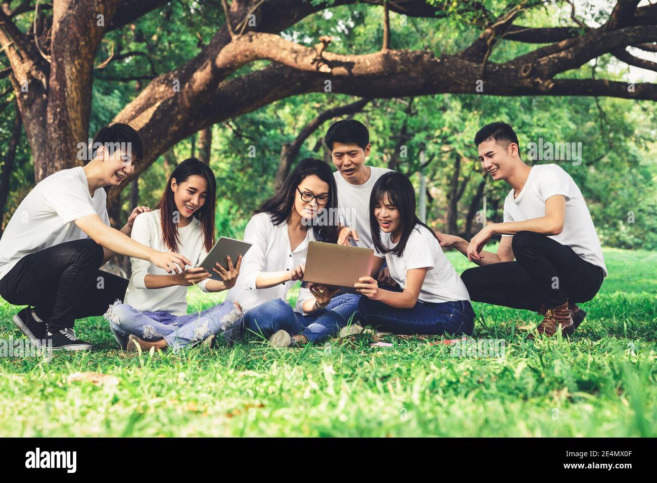 Team of young students studying in a group project in the park of university or school. Happy learning, community teamwork and youth friendship Stock Photo