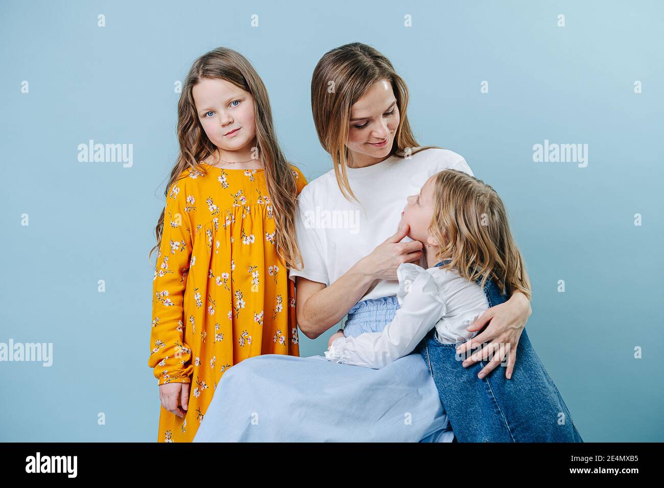 Mom and two daughters socialize together on a blue background Stock Photo