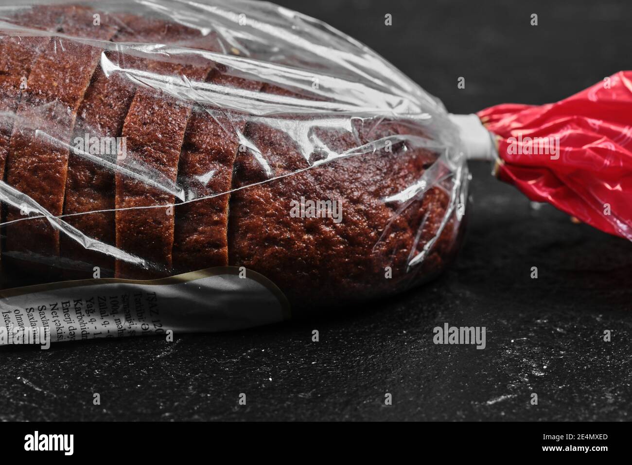 Sliced black rye bread in plastic bag on dark background Stock Photo