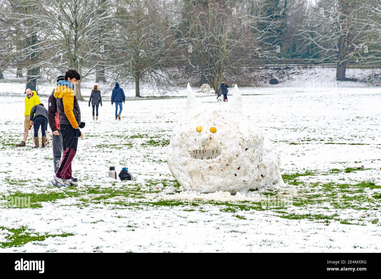 A couple of men have fun making a large caterpillar like creature, sculpted out of snow in Prospect Park, Reading, UK in the middle of winter. Stock Photo