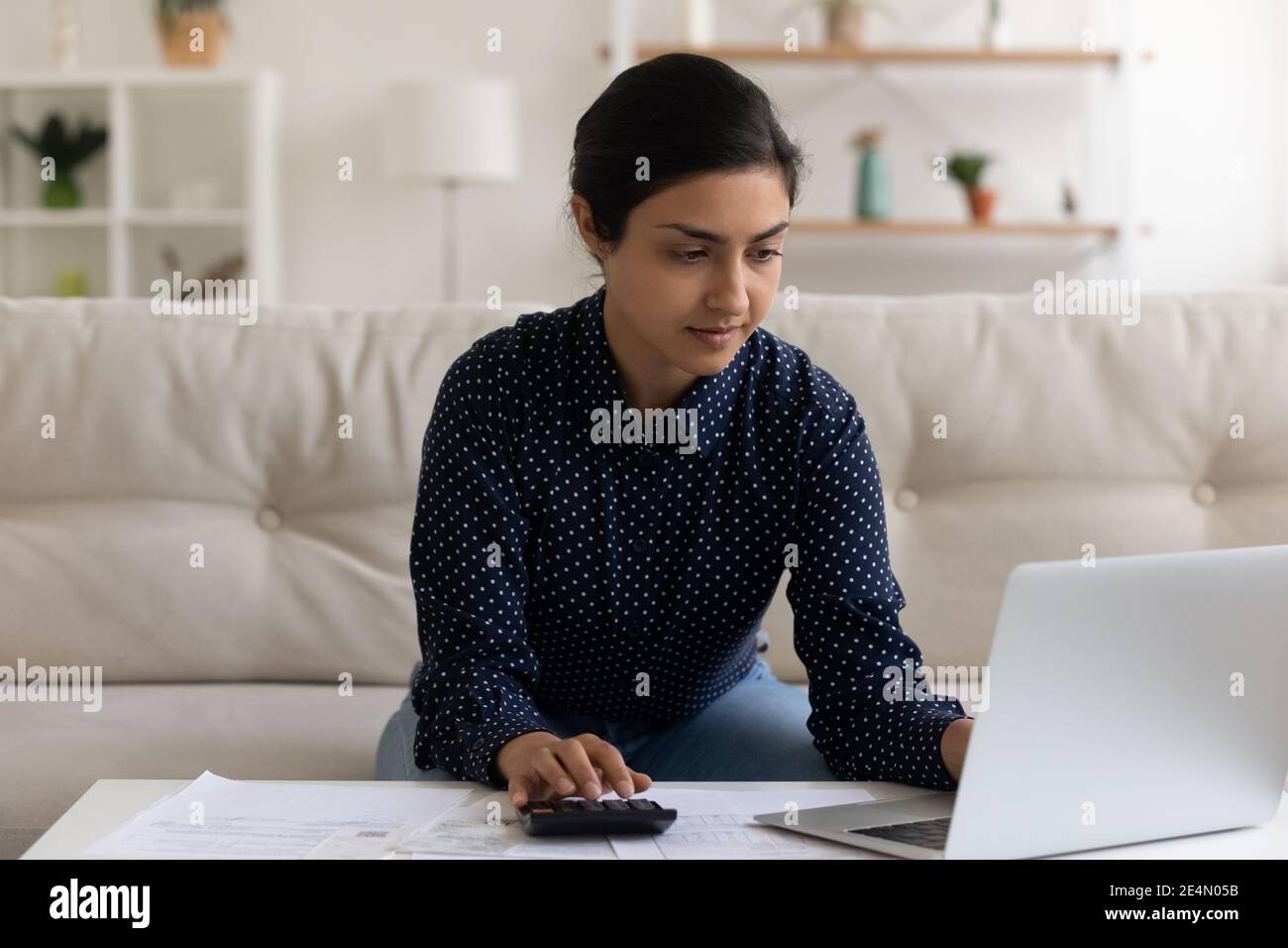Focused young mixed race businesswoman pay business taxes online stock