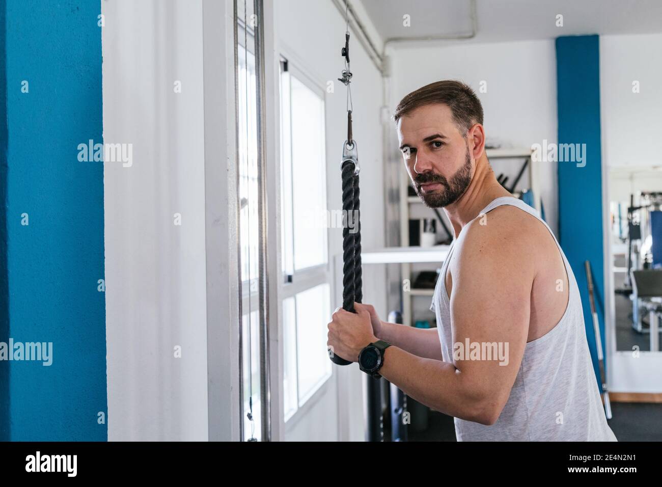A man doing triceps exercises in the gym. Looking at the camera. Health and wellness concept Stock Photo