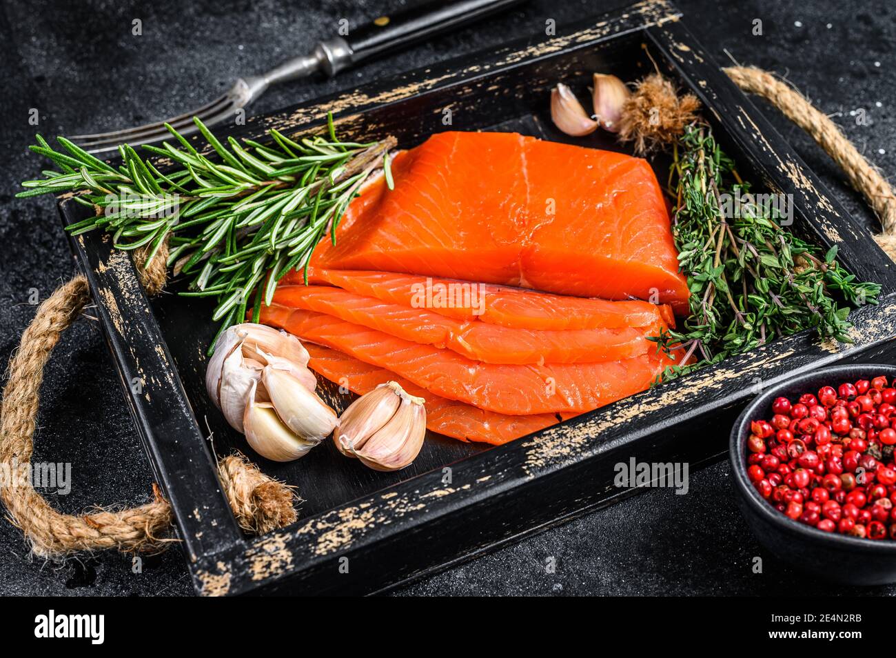 Smoked sliced salmon fillet in a wooden tray with herbs. Black ...