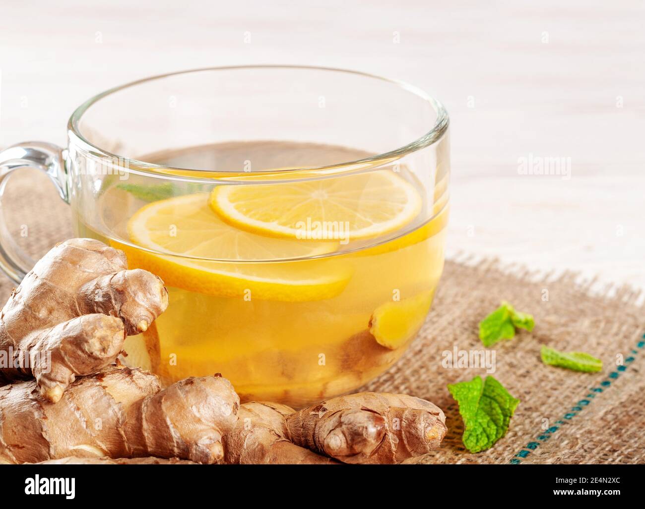 Glass cup of hot ginger tea with lemon and peppermint. Winter herbal
