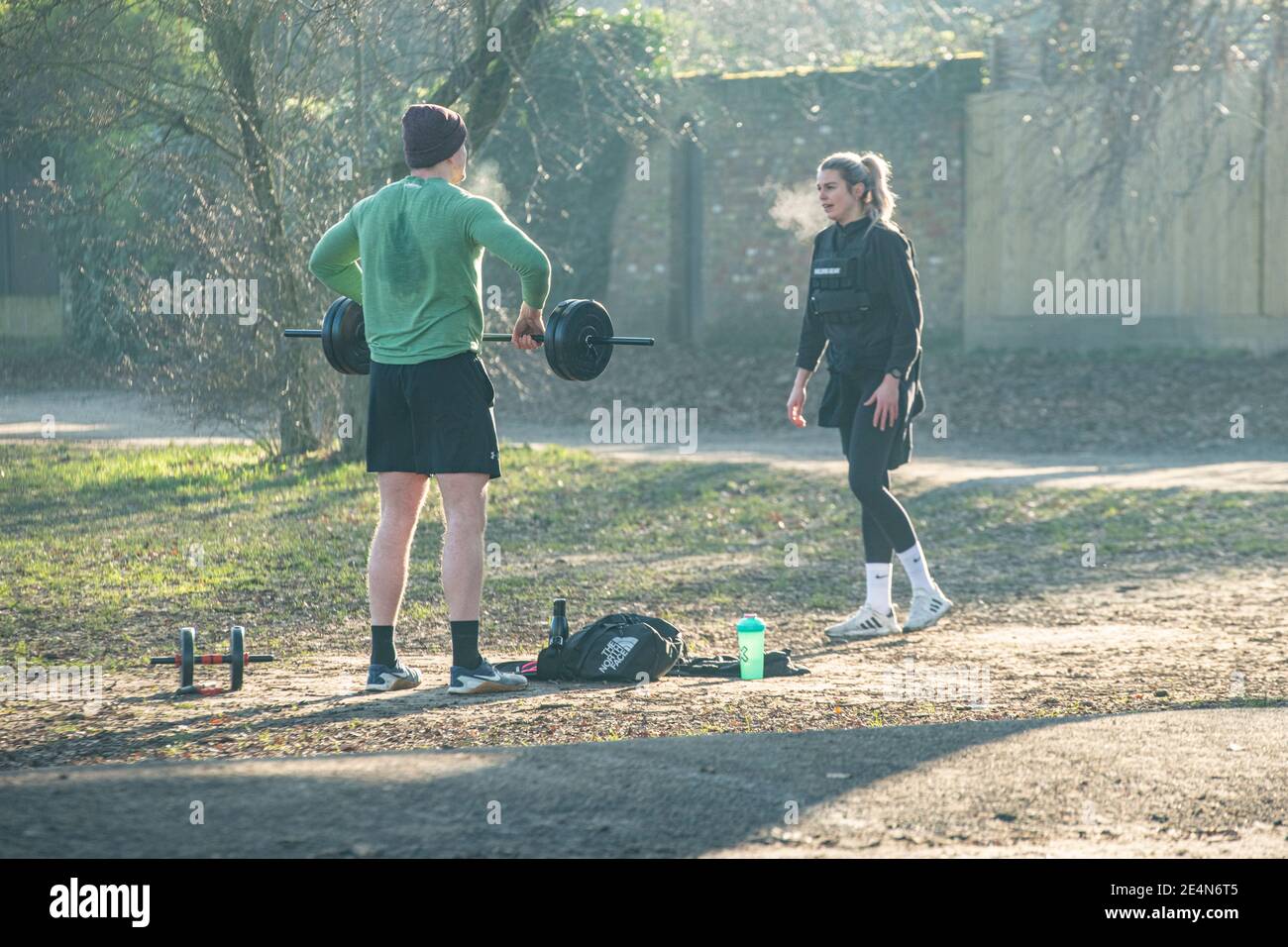 A man and a woman keep fit and lift weights during lockdown in a London park Stock Photo