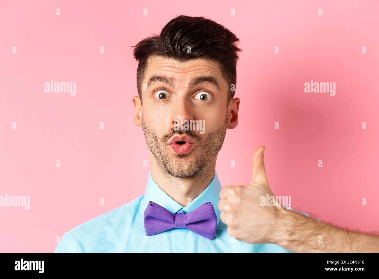 Close-up of funny guy with moustache, say wow and showing thumb up in  approval, checking out something cool, recommending product, standing on  pink Stock Photo - Alamy