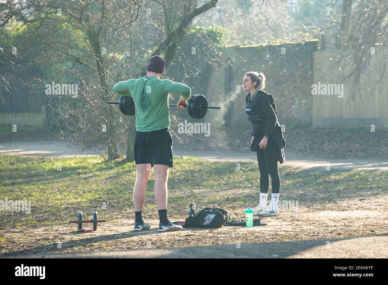 A man and a woman keep fit and lift weights during lockdown in a London park Stock Photo