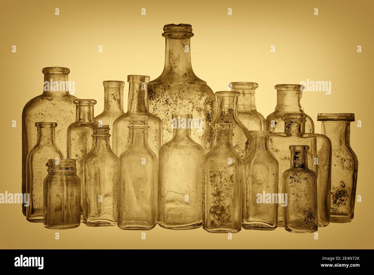 A collection of old antique bottles with a sepia tone. There are 18 ancient bottles, and they are dirty. Focus on the front row. Stock Photo