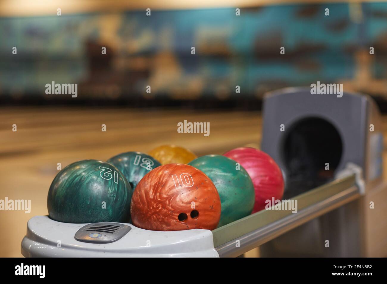 Background image of several bowling balls on rack in bowling alley