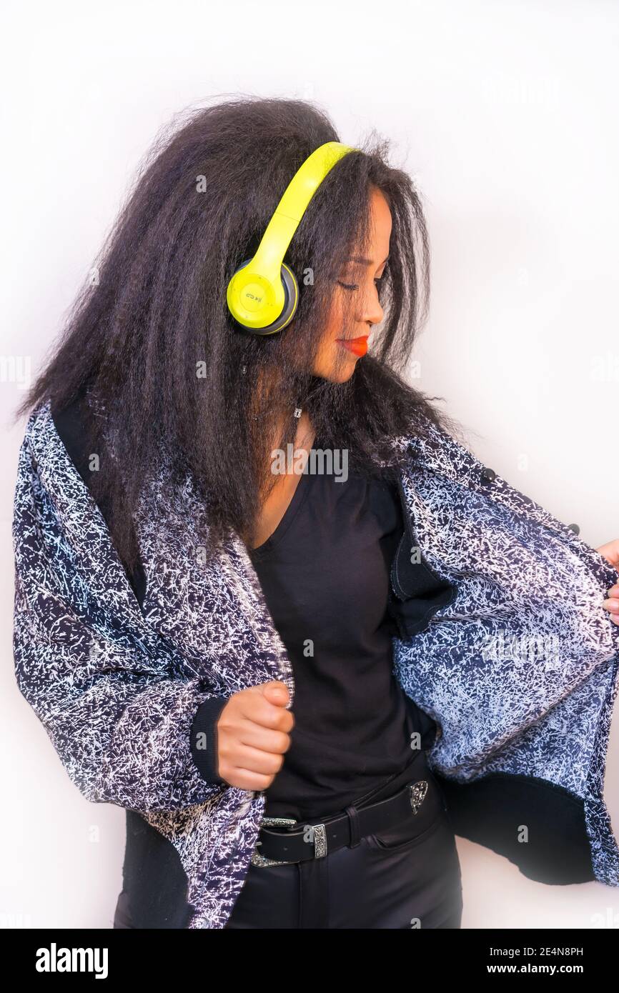 A vertical closeup of an attractive Hispanic female enjoying music with ...