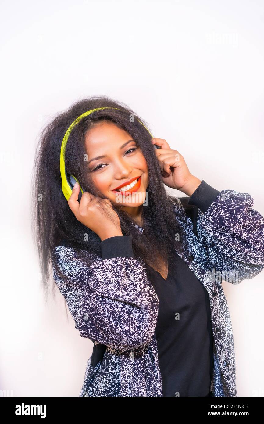 A vertical closeup of a pretty smiling Hispanic female enjoying music ...