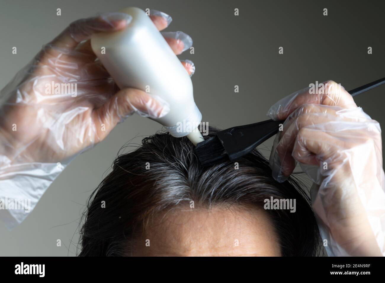 Closeup woman hands dyeing hair using black brush. Middle age woman  colouring dark hair with gray roots at home Stock Photo - Alamy